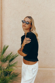Woman leaning on a wall wearing the oval sunglasses