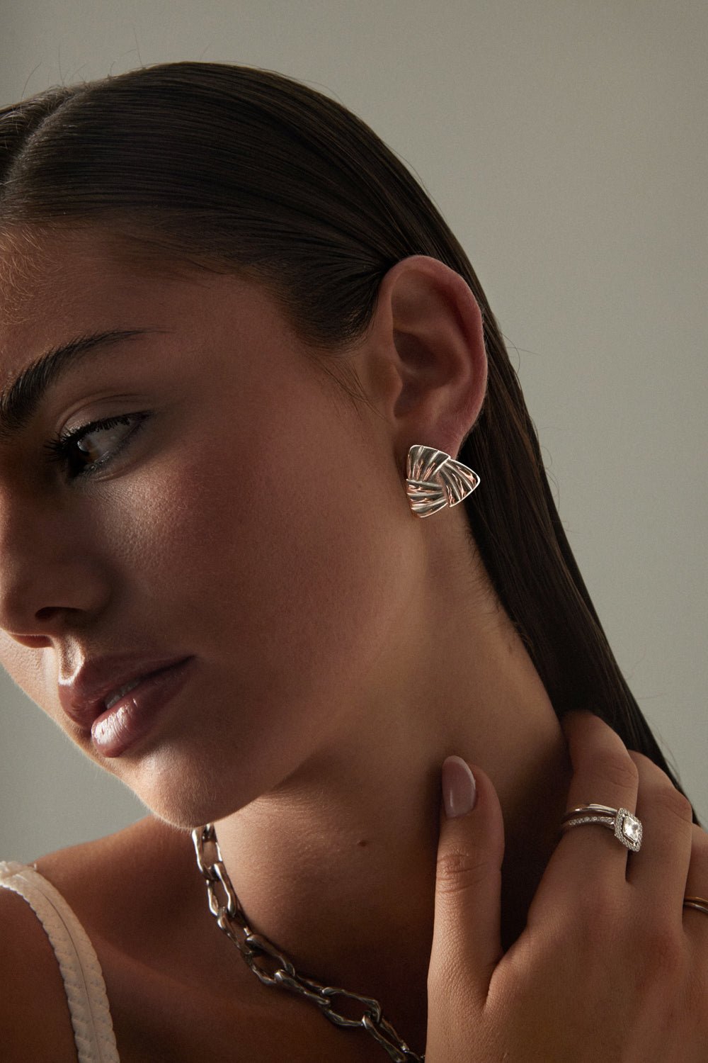 Model touching her neck, triangle stud visible