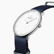 Three-quarter view of the thin silver-tone case on a navy fabric strap.