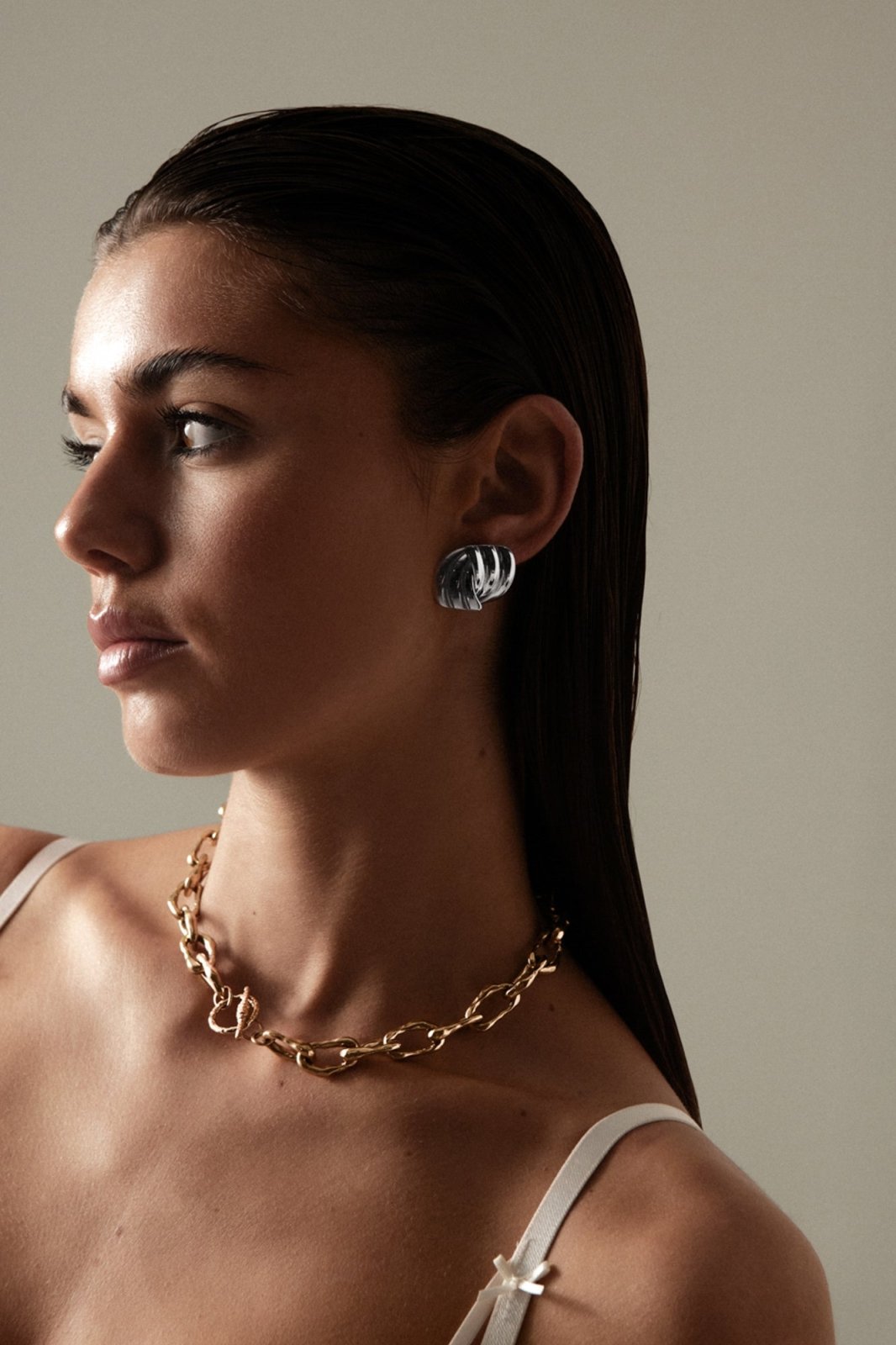 Model in profile wearing the stud and a chain necklace